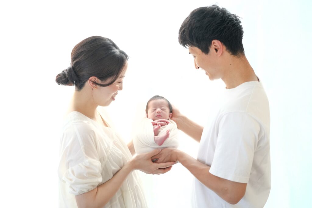 飯田市のニューボーンフォト出張撮影｜赤ちゃんをパパとママがやさしく持ち上げている写真