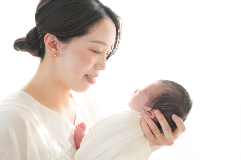 飯田市のニューボーンフォト出張撮影｜ママが白い服で赤ちゃんを優しく抱っこしている写真