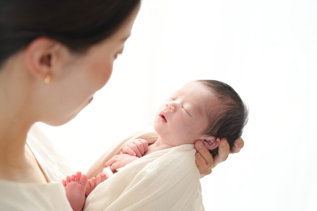 飯田市のニューボーンフォト出張撮影｜パパとママの手が赤ちゃんの足を包み込んでいる写真