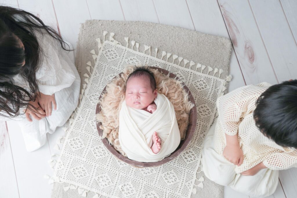 安曇野市でのニューボーンフォト｜お兄ちゃんとお姉ちゃんが赤ちゃんを見つめているの写真