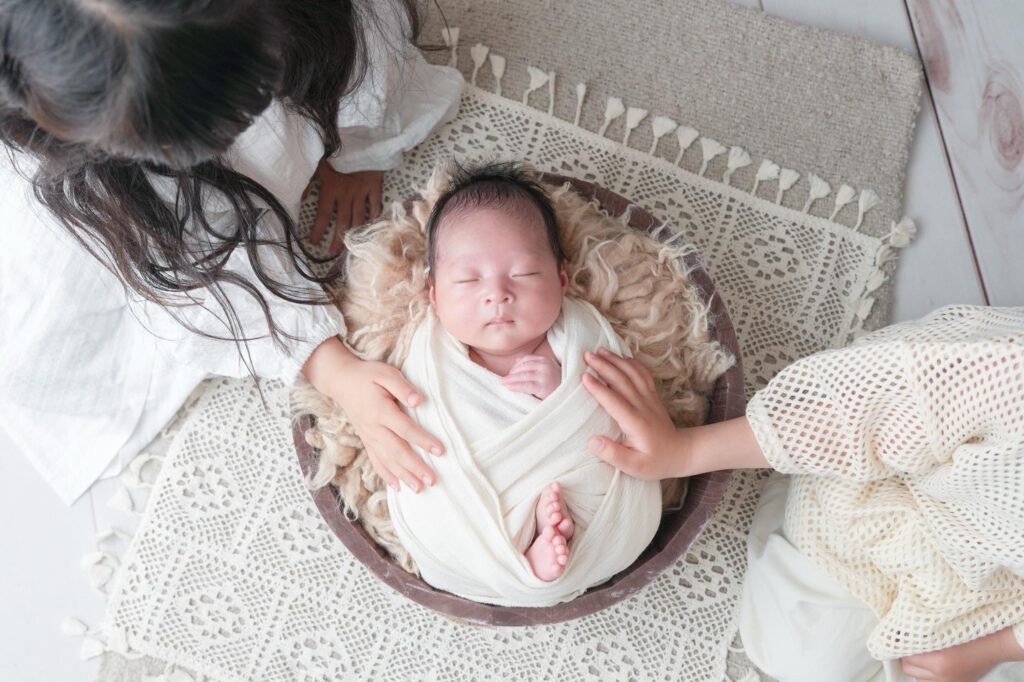 安曇野市でのニューボーンフォト｜お兄ちゃんとお姉ちゃんが赤ちゃんに手を添えているの写真