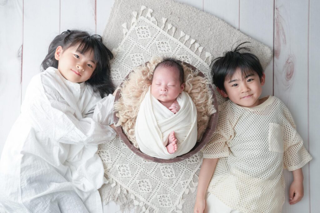 安曇野市でのニューボーンフォト｜横に寝転んで赤ちゃんと一緒に写るお兄ちゃんとお姉ちゃんの写真