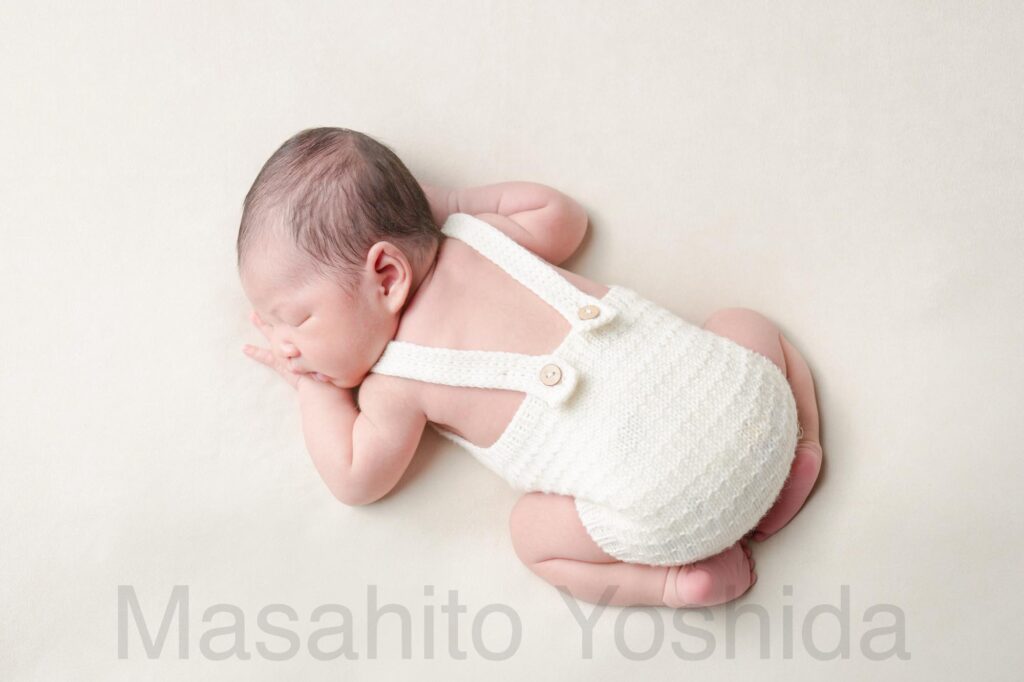 下伊那郡松川町のニューボーンフォト出張撮影｜白い背景、白い服を着てうつぶせで寝ている赤ちゃんの背中の写真