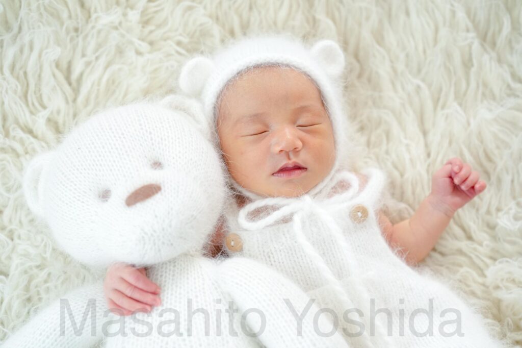 上伊那郡南箕輪村でニューボーンフォト｜フロカティの上でくまのロンパースを着て、くまのぬいぐるみを抱く赤ちゃん。